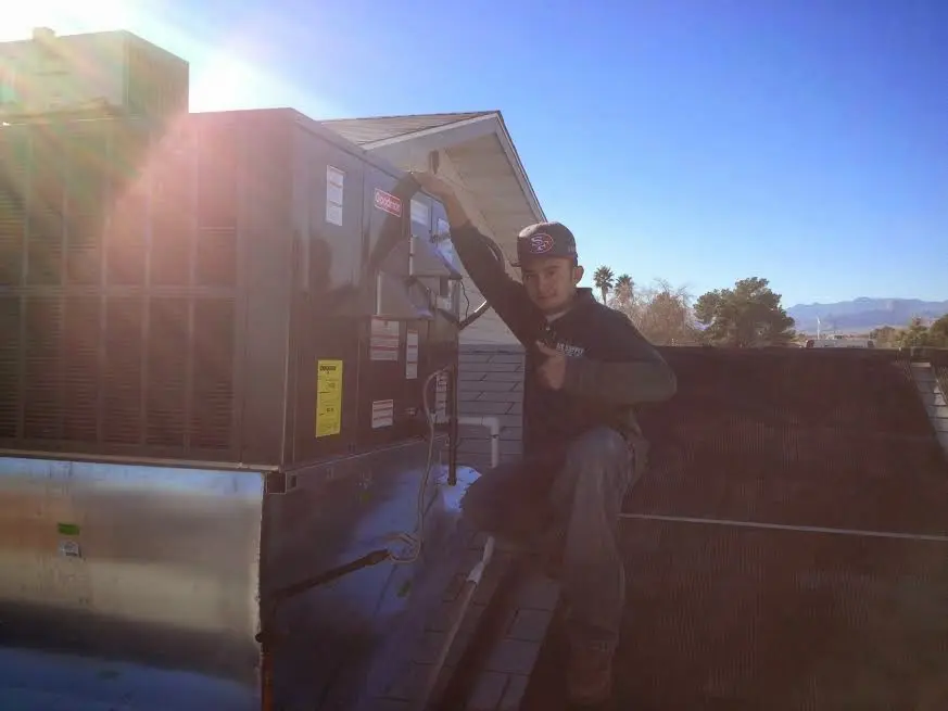 HVAC technician performing AC Tune-Up on a rooftop unit in Wailuku